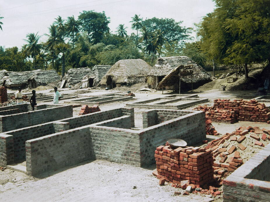 Im Dorf Canoor (Indien) finanzierten wir den Bau von 25 Backsteinhäuschen. Im Hintergrund stehen die alten, baufälligen Lehmhütten mit wasserdurchlässigen Strohdächern