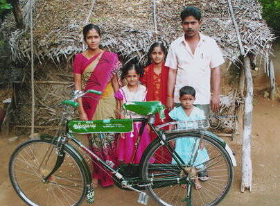 Der Vater des Mädchens Monisha (neben dem Vater) in Vandavasi (Indien) erhielt ein Fahrrad, mit dem er zur Arbeit fährt